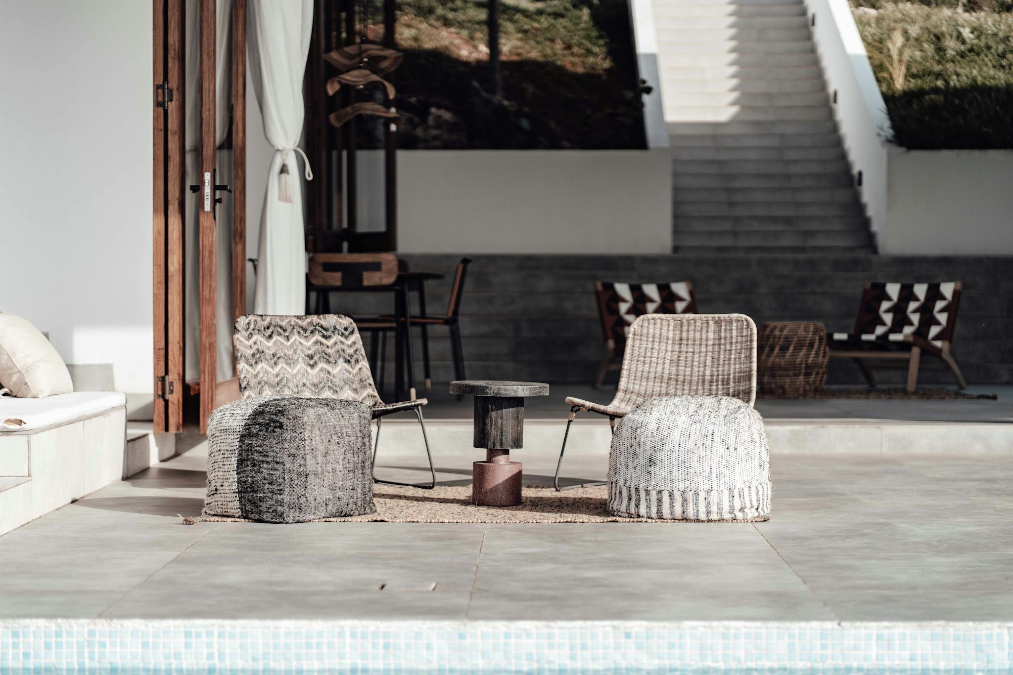 Luxurious outdoor seating arrangement by a pool, featuring modern chairs and decor in a minimalist style.